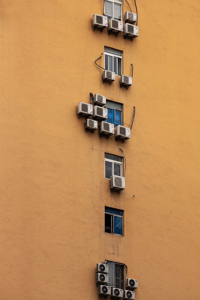 Urban apartment exterior with multiple air conditioners on a vibrant wall, showcasing city architecture.
