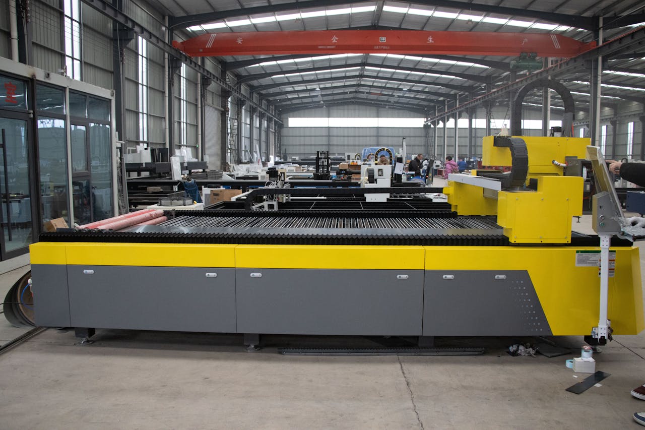 Modern CNC laser machine in a spacious manufacturing factory environment.